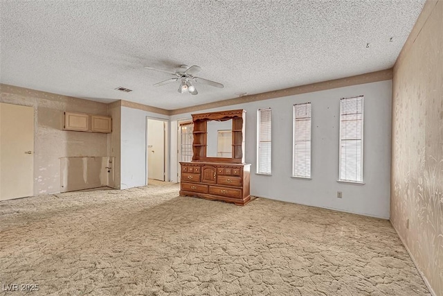 unfurnished bedroom with ceiling fan, light carpet, and a textured ceiling