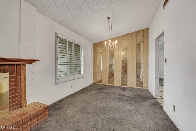 unfurnished dining area with a fireplace, carpet flooring, a chandelier, and a textured ceiling