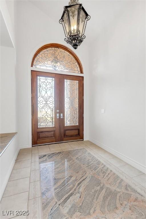 tiled entrance foyer with an inviting chandelier