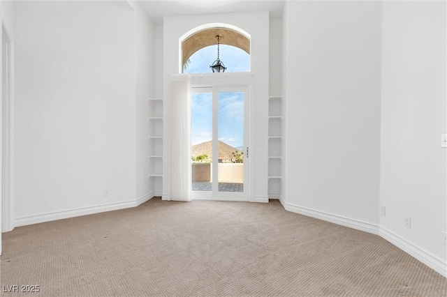 spare room featuring a mountain view, built in features, and light colored carpet