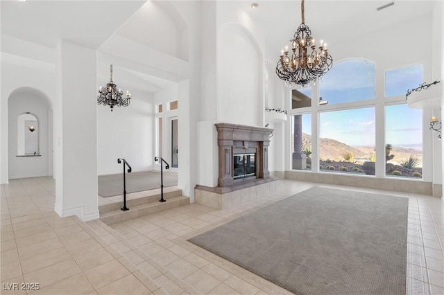 unfurnished living room featuring a mountain view, light tile patterned flooring, a chandelier, and a high ceiling