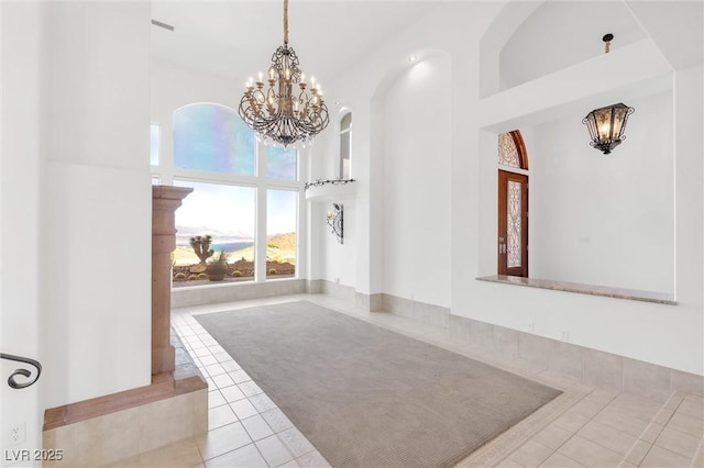 foyer entrance featuring an inviting chandelier, light tile patterned flooring, and a high ceiling