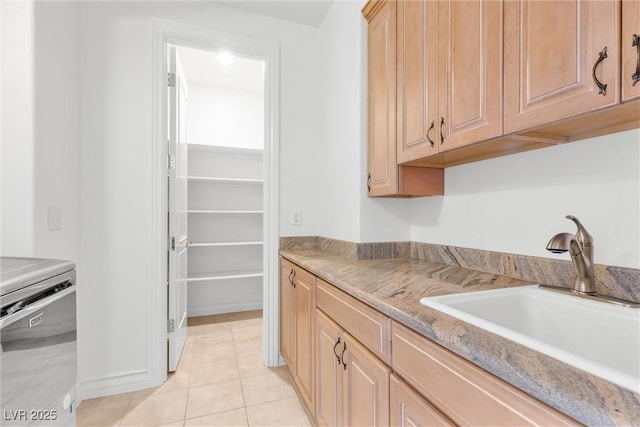 kitchen featuring light brown cabinetry, sink, light tile patterned floors, and light stone countertops