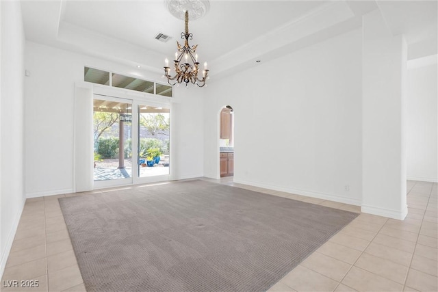 unfurnished room featuring a tray ceiling, a chandelier, and light tile patterned flooring