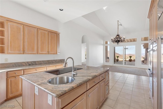 kitchen with sink, light tile patterned floors, a kitchen island with sink, light stone countertops, and light brown cabinets