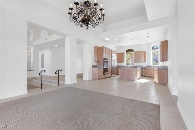 kitchen featuring light brown cabinetry, sink, a center island, light tile patterned floors, and stainless steel double oven