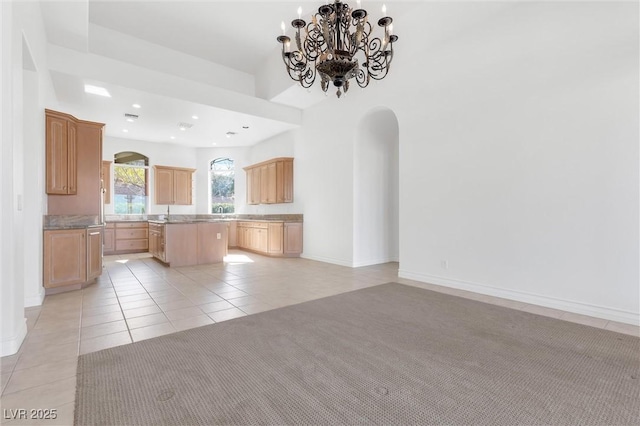 kitchen with a notable chandelier, light colored carpet, a center island, and light brown cabinets