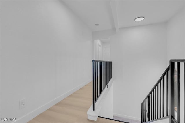 stairway featuring baseboards, wood finished floors, and beam ceiling