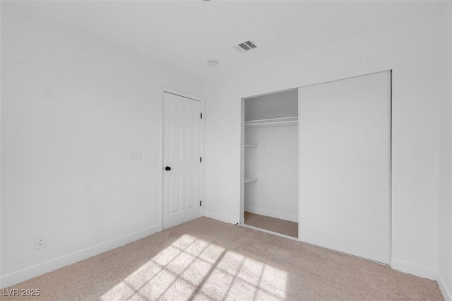 unfurnished bedroom with light carpet and a closet