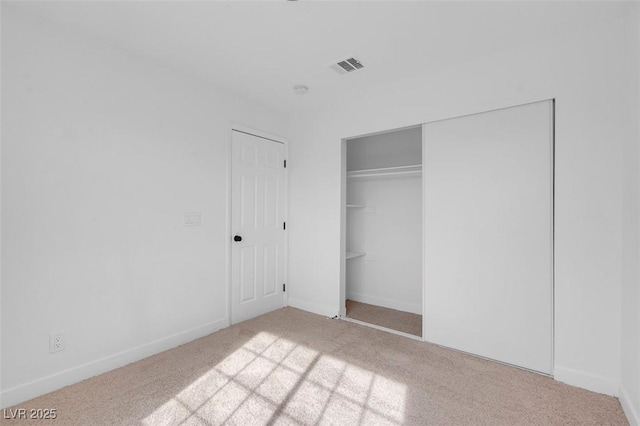 unfurnished bedroom featuring baseboards, a closet, visible vents, and carpet