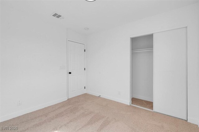 unfurnished bedroom with a closet and light carpet