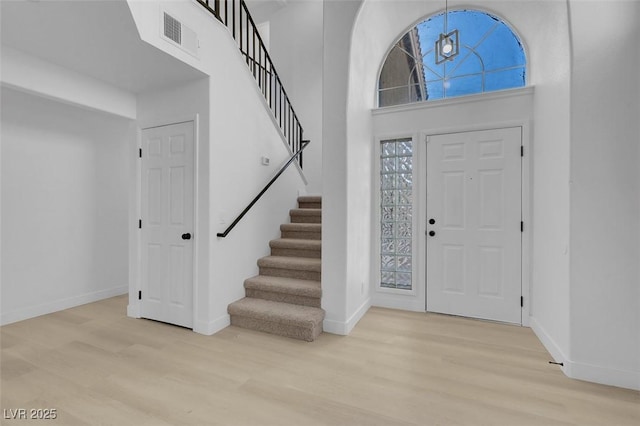 entryway with a towering ceiling and light hardwood / wood-style floors