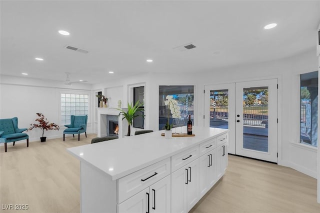 kitchen with a center island, visible vents, light wood-style floors, white cabinetry, and light countertops