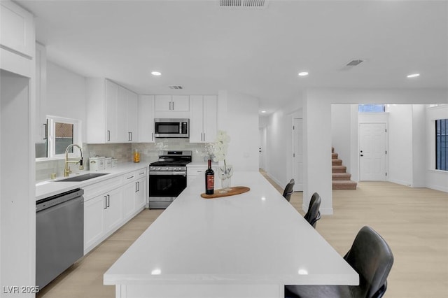 kitchen with a kitchen island, white cabinetry, appliances with stainless steel finishes, and sink