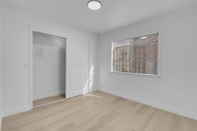 unfurnished bedroom with wood finished floors, a closet, and baseboards