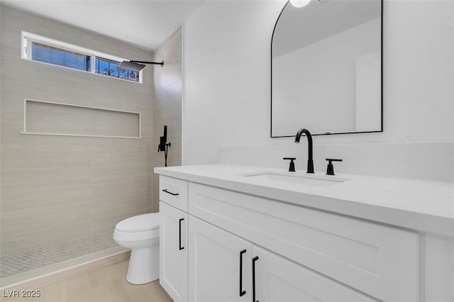 bathroom featuring tiled shower, vanity, and toilet
