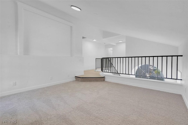 carpeted empty room featuring vaulted ceiling