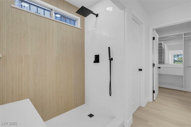 bathroom with hardwood / wood-style flooring, plenty of natural light, and a tile shower