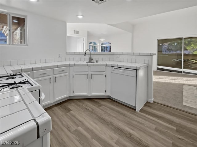 kitchen with sink, white cabinets, tile counters, white appliances, and light hardwood / wood-style flooring