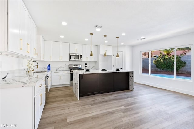 kitchen featuring sink, white cabinetry, decorative light fixtures, a center island, and stainless steel appliances