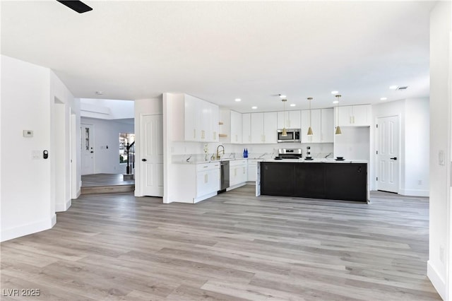 kitchen featuring pendant lighting, sink, appliances with stainless steel finishes, white cabinetry, and a center island