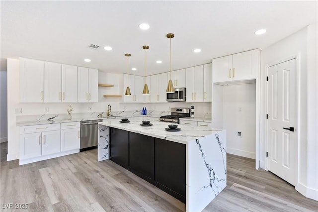 kitchen featuring stainless steel appliances, a center island, hanging light fixtures, and white cabinets