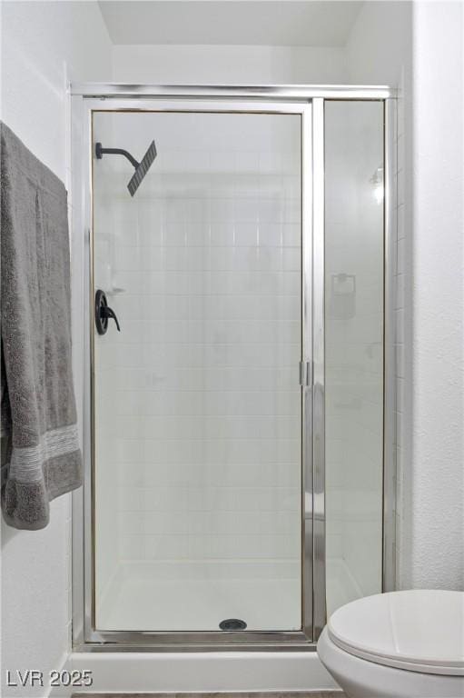 bathroom with toilet and a shower with shower door