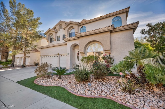 mediterranean / spanish house featuring driveway, an attached garage, and stucco siding