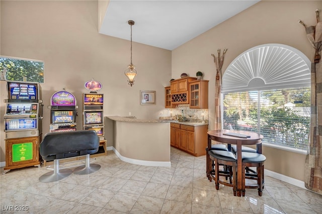 kitchen featuring kitchen peninsula, high vaulted ceiling, decorative backsplash, and pendant lighting