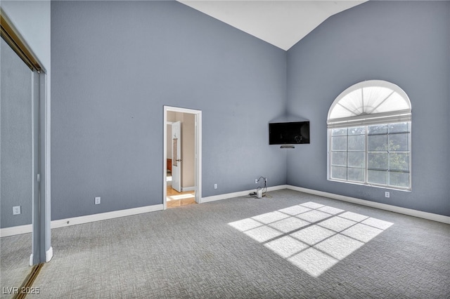 carpeted empty room with high vaulted ceiling