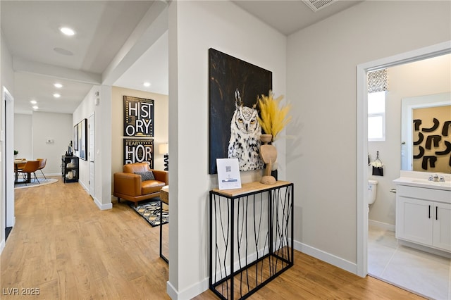 hallway with sink and light hardwood / wood-style flooring