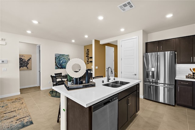 kitchen with sink, decorative backsplash, a kitchen island with sink, stainless steel appliances, and dark brown cabinets