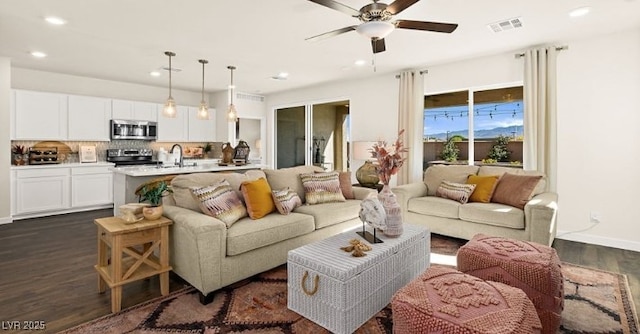 living room featuring ceiling fan, dark hardwood / wood-style floors, and sink