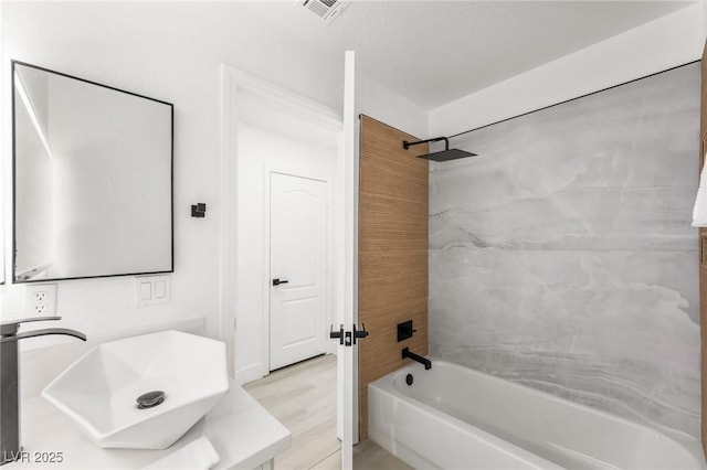 bathroom featuring tiled shower / bath, wood-type flooring, and sink