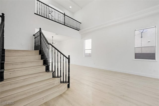 stairway featuring hardwood / wood-style flooring, a towering ceiling, and an inviting chandelier