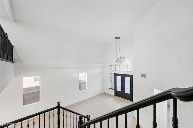 staircase with a towering ceiling, wood-type flooring, and french doors