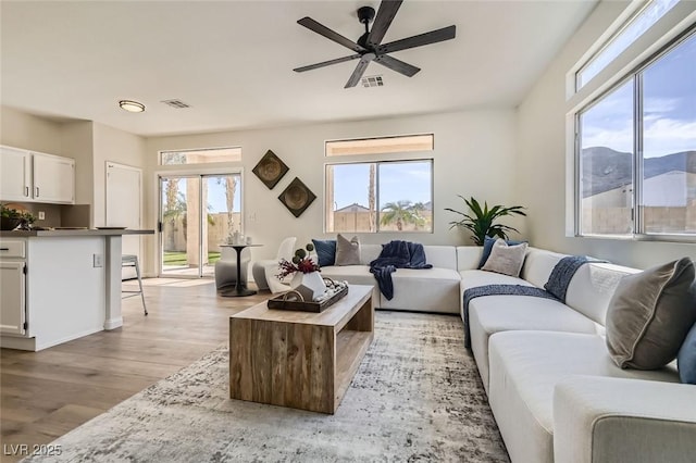 living room featuring ceiling fan, a mountain view, and light hardwood / wood-style floors