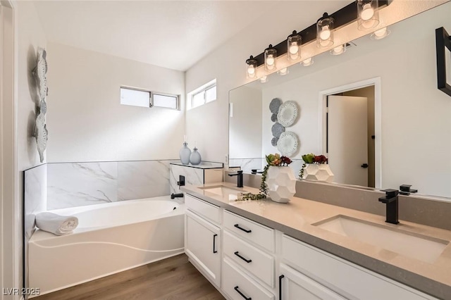 bathroom featuring vanity, wood-type flooring, and a tub to relax in