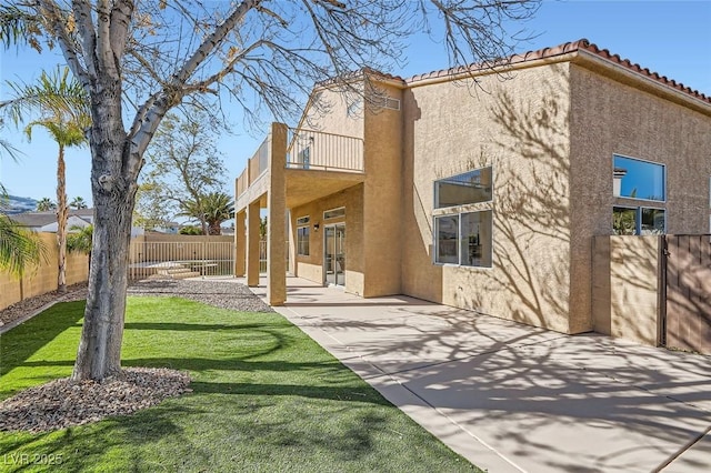 back of property featuring a balcony, a lawn, and a patio area