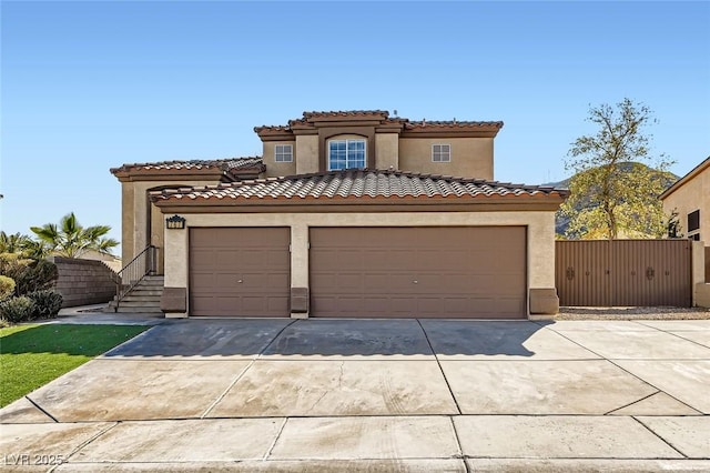 mediterranean / spanish house featuring a garage, concrete driveway, a tile roof, and stucco siding