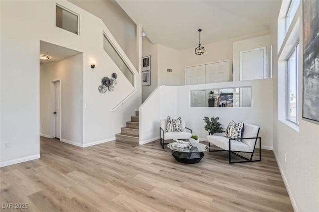 sitting room with a high ceiling, baseboards, light wood finished floors, and stairs