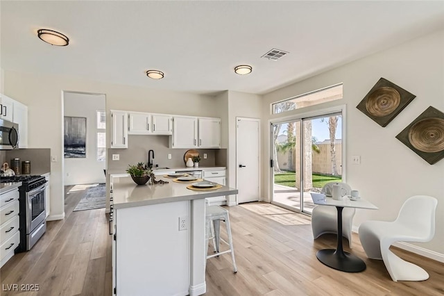 kitchen with white cabinetry, appliances with stainless steel finishes, sink, and light hardwood / wood-style floors