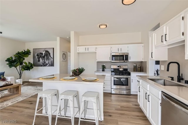 kitchen with white cabinetry, sink, stainless steel appliances, and hardwood / wood-style floors