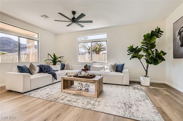 living room featuring a mountain view, ceiling fan, and light wood-type flooring