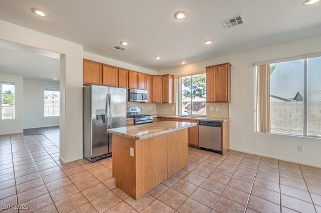 kitchen featuring light tile patterned flooring, sink, backsplash, a center island, and stainless steel appliances