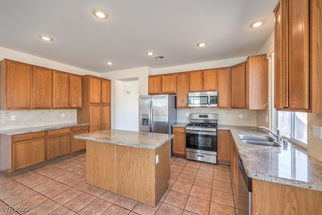 kitchen featuring sink, light tile patterned floors, appliances with stainless steel finishes, light stone counters, and a kitchen island