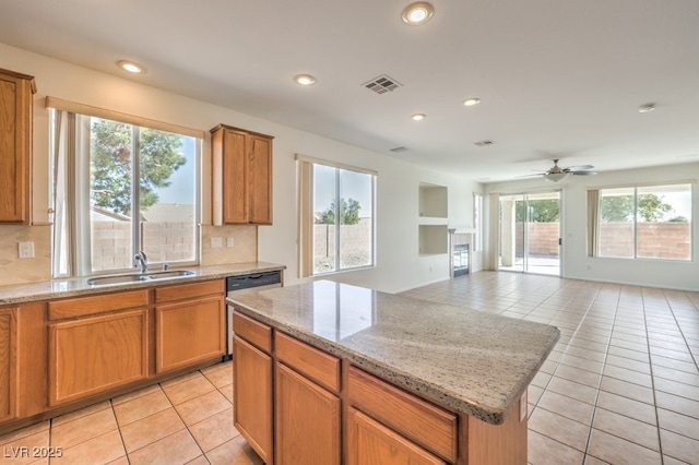 kitchen featuring stainless steel dishwasher, a center island, sink, and light tile patterned floors