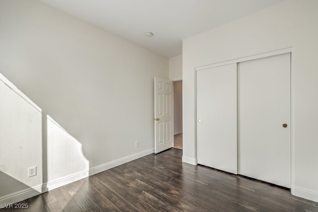 unfurnished bedroom with dark hardwood / wood-style flooring and a closet