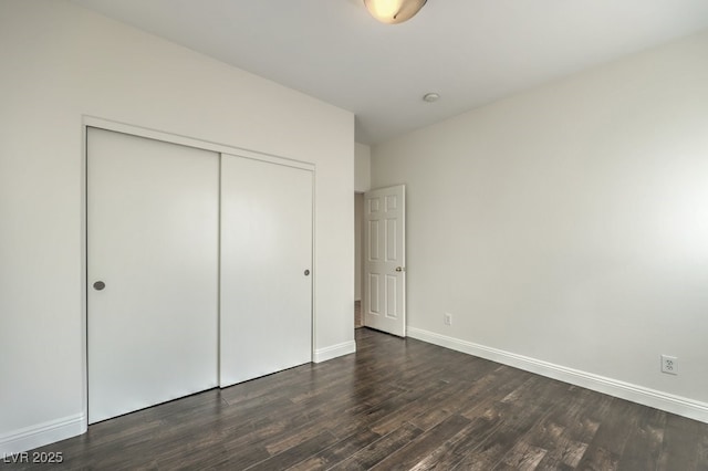 unfurnished bedroom featuring dark hardwood / wood-style flooring and a closet