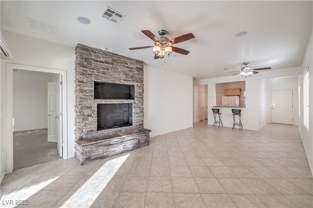 unfurnished living room with ceiling fan, a fireplace, and light tile patterned floors